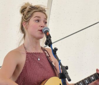 Izzy Burns is an American folk pop singer from Moscow, Idaho, who sings because she once couldn’t. Despite facing significant medical challenges early in life, including an emergency tracheostomy surgery that initially left her without a voice as a child for the first two years of her life, Izzy has defied the odds to become a talented musician and singer. After multiple surgeries and years of therapy, she was able to not just speak, but sing and Izzy began to immerse herself in singing, playing guitar, and writing songs. Her debut project, You Can’t Stop Me Now, released in 2019, and her follow-up project, A Heartbeat of Your Time, showcase her remarkable journey and musical versatility. Her career took a pivotal turn when she sat on a plane next to Mellad Abeid, a guitar professor at Gonzaga University, who helped refine her songwriting and production skills. Izzy’s story of overcoming early life adversity to become a celebrated artist is a testament to her strength and dedication. Her music, available on major streaming platforms, and reflects her deep passion and resilience.
